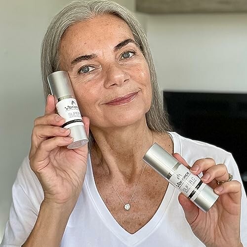 Woman holding skincare products and smiling.